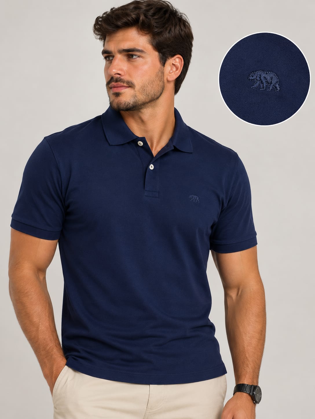 Homem vestindo polo piquet azul-marinho Bransk com calça bege, ao lado de detalhe ampliado do urso bordado