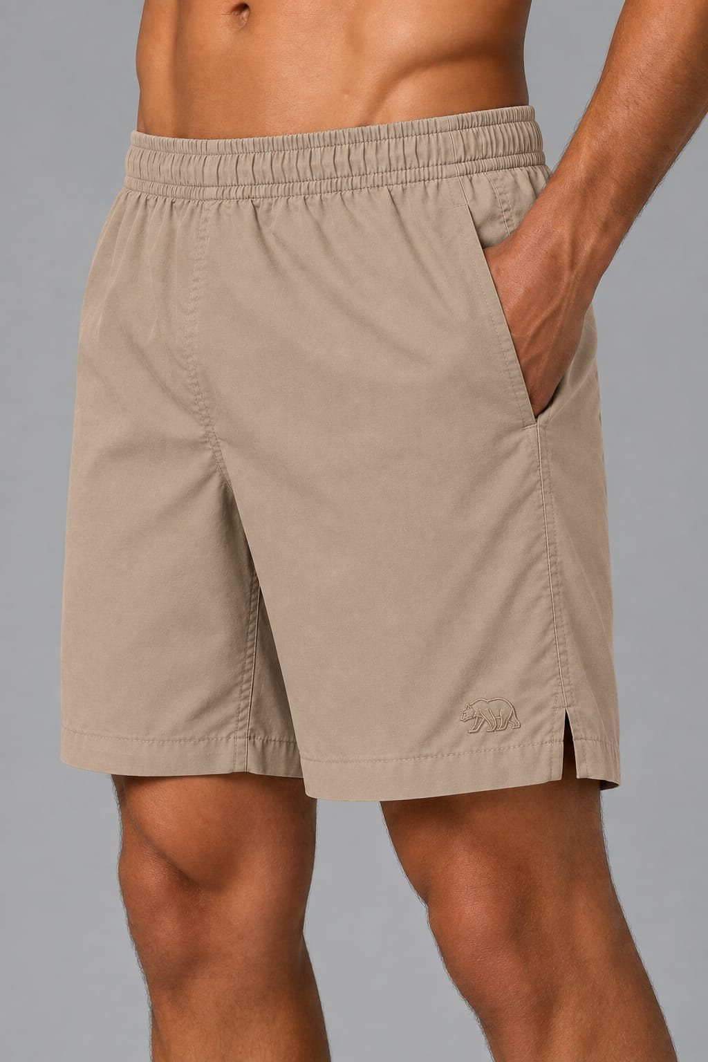 Detalhe de short de tactel bege Bransk com cós elástico e urso bordado.